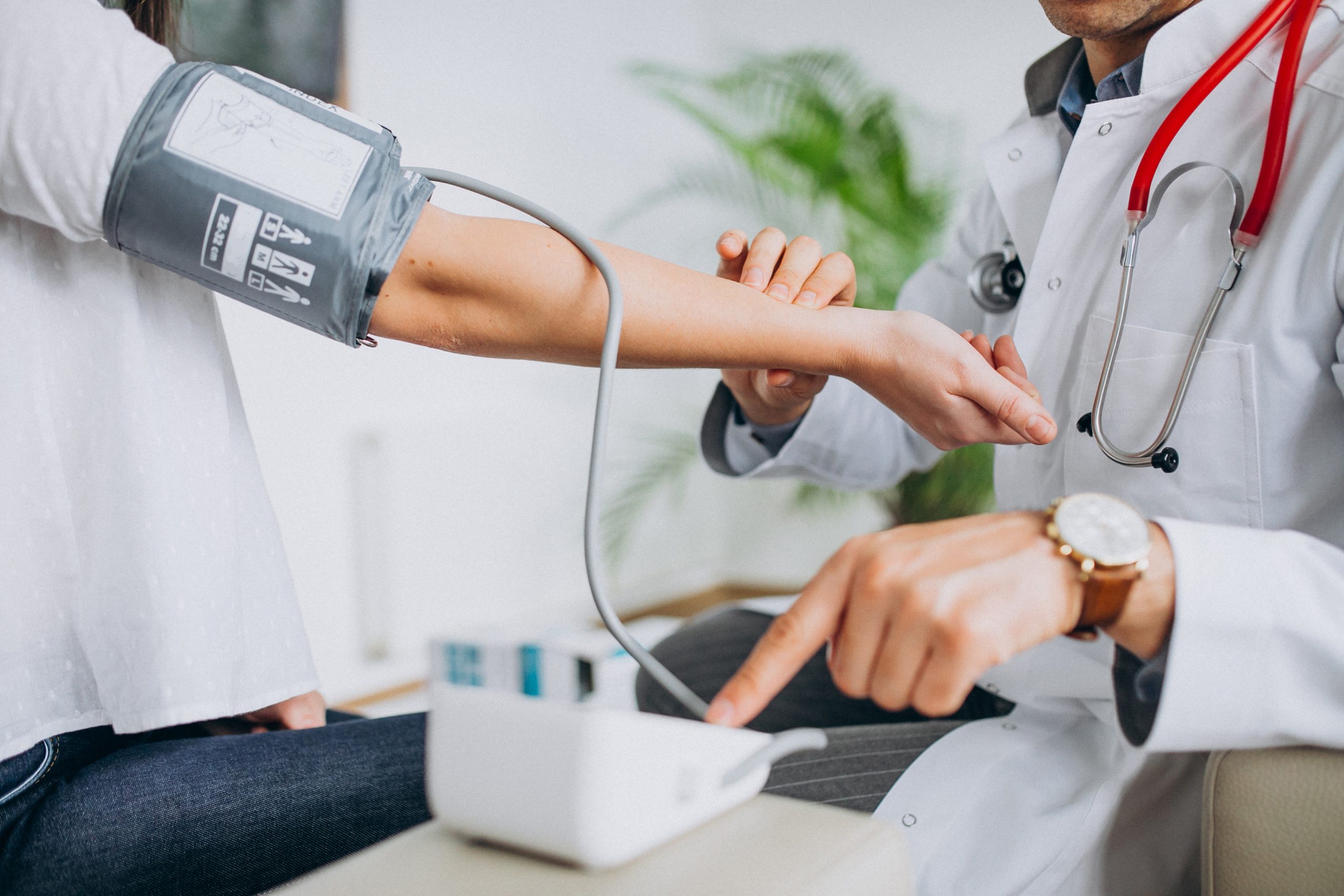 Young male psysician with patient measuring blood pressure scaled